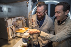 Kyle Nel, executive director, Lowe's Innovation Labs, left, and Jason Dunn, CTO and co-founder, Made in Space, examine a 3D printer in a mock-up of the International Space Station (ISS) in New York on Wednesday, October 28, 2015. Lowe’s Innovation Labs, the disruptive innovation hub of Lowe’s Companies, Inc., has partnered with aerospace company Made in Space, to become the first to launch a commercial 3D printer to space. The printer, the first permanent additive manufacturing facility for the ISS, will bring tools and technology to astronauts in space.(Jim Sulley/Newscast Creative)