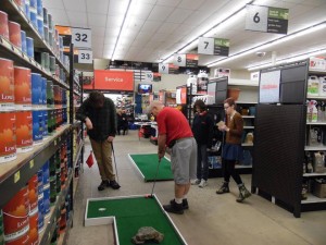 Employees at Dawson's True Value Hardware play mini golf at the store during an employee party.