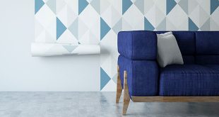 A blue sofa in front of geometric wallpaper being applied