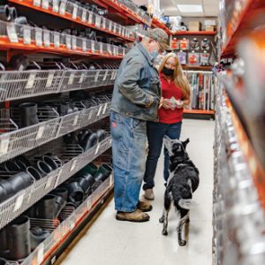 A woman in a hardware store helping a customer with pipe fittings